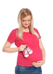 Beautiful pregnant woman holding baby booties near tummy on white background