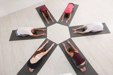 Photo of Grouppeople practicing yoga on mats indoors, above view