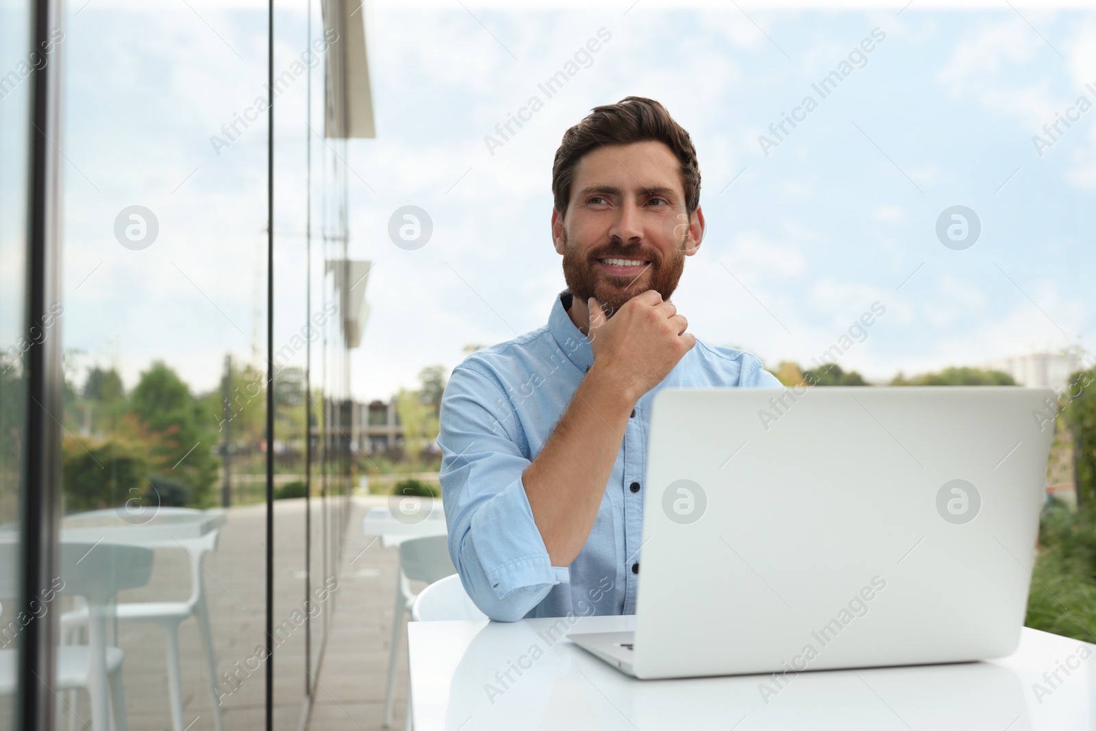 Photo of Handsome man with laptop in outdoor cafe