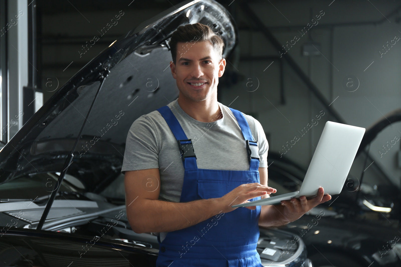 Photo of Mechanic with laptop doing car diagnostic at automobile repair shop