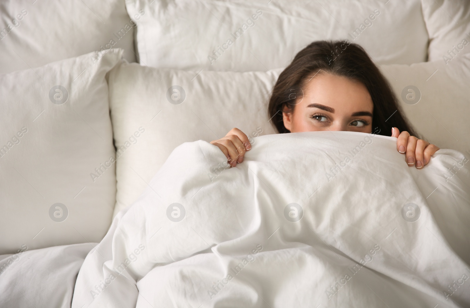 Photo of Beautiful young woman wrapped with soft blanket relaxing in bed at home, above view