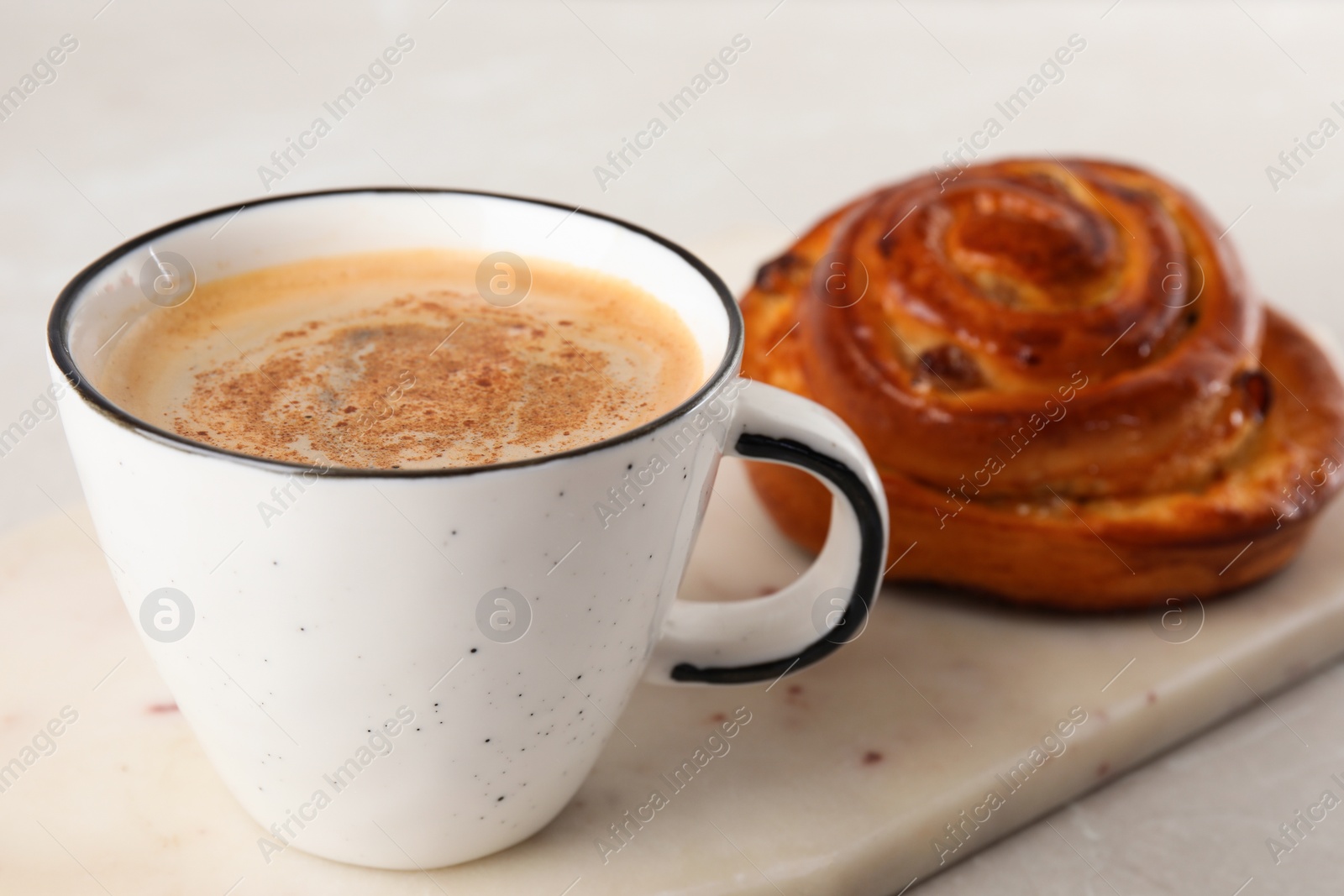 Photo of Delicious bun and coffee on light table. Sweet pastries