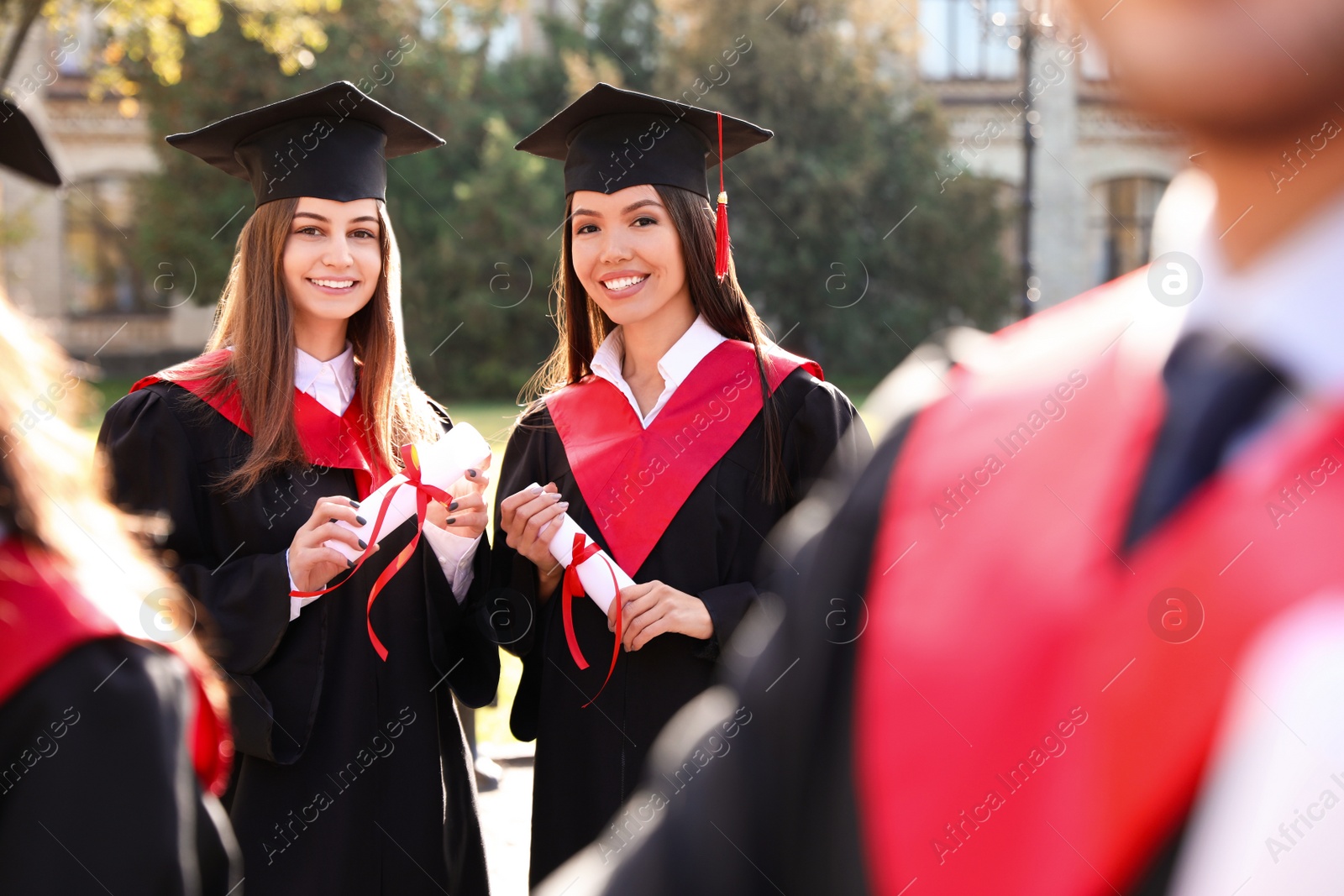 Photo of Happy students with diplomas outdoors. Graduation ceremony