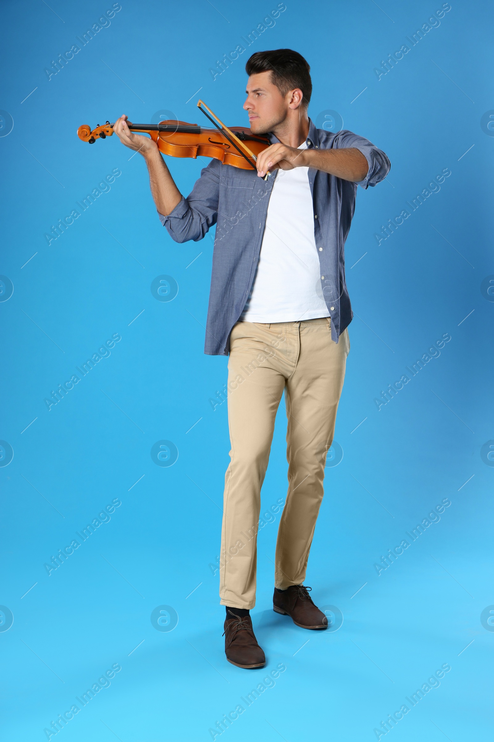 Photo of Man playing violin on light blue background