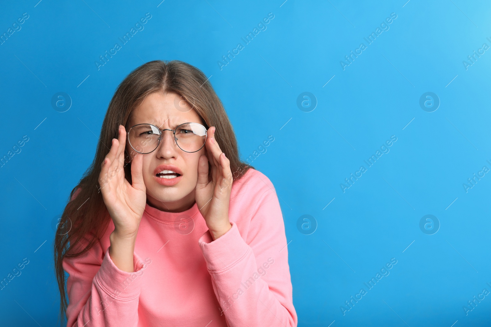 Photo of Young woman with glasses on blue background. Vision problems