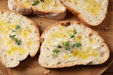 Photo of Tasty bruschettas with oil and thyme on wooden plate, top view