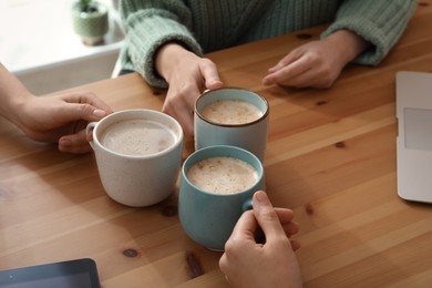 Women with cups of coffee at table in cafe, closeup