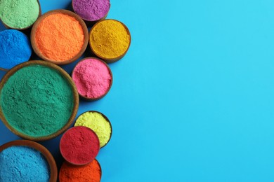 Photo of Colorful powders in bowls on light blue background, flat lay with space for text. Holi festival celebration