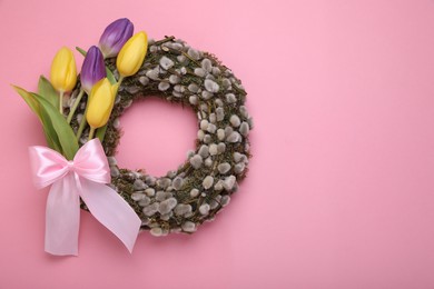 Photo of Wreath made of beautiful willow, colorful tulip flowers and bow on pink background, top view. Space for text
