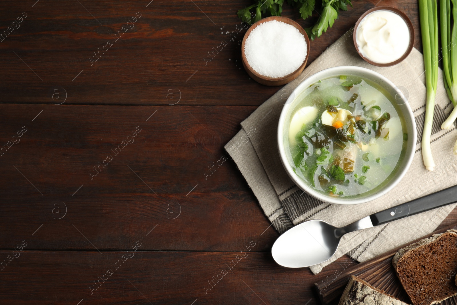 Photo of Delicious sorrel soup served on brown wooden table, flat lay. Space for text