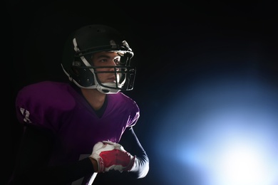 American football player wearing uniform on dark background. Space for text