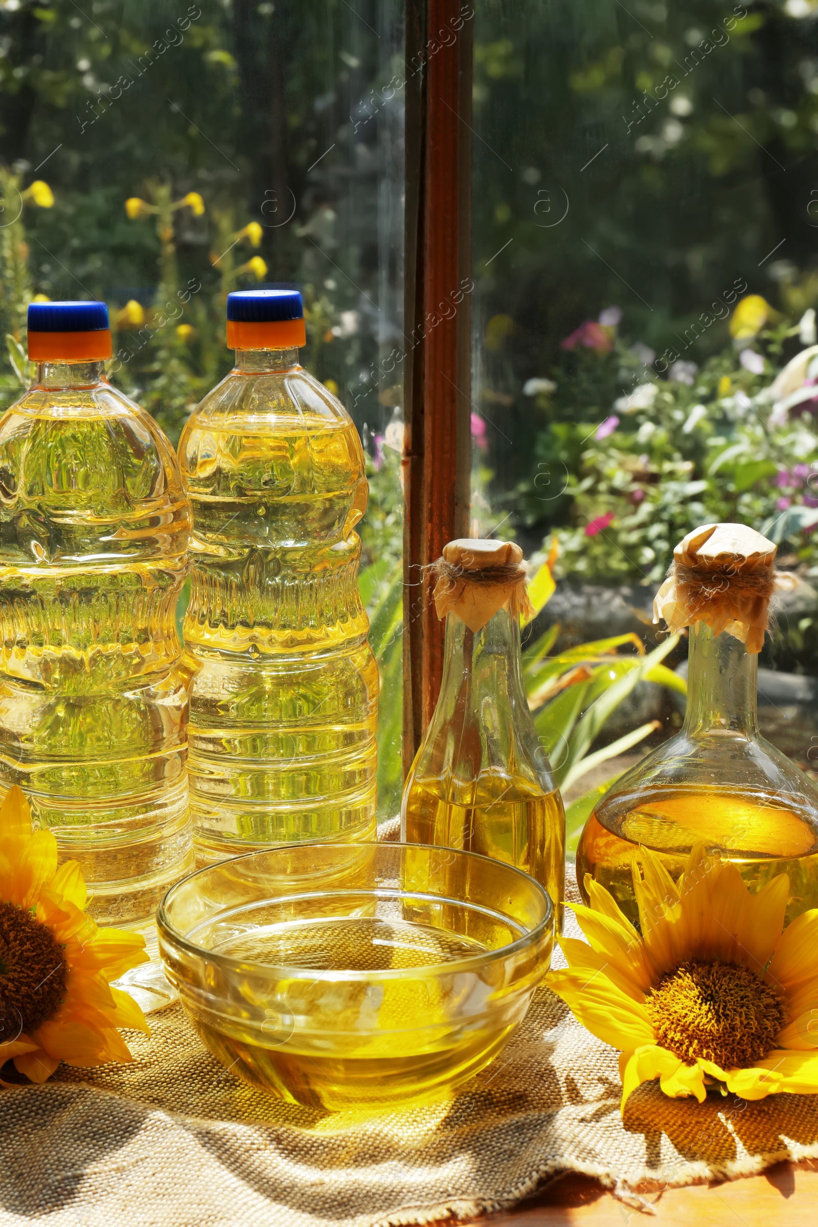 Photo of Organic sunflower oil and flowers on window sill indoors