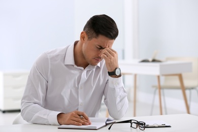 Photo of Stressed man at white table in office