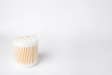 Photo of New cotton buds in container on white background. Space for text