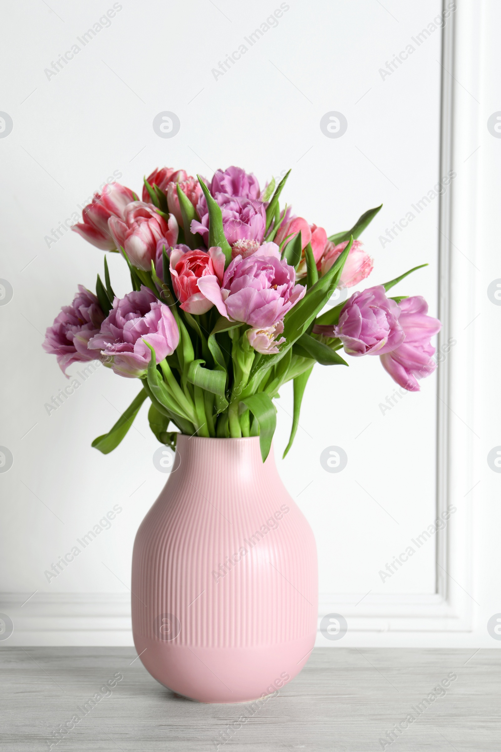 Photo of Beautiful bouquet of colorful tulip flowers on floor near white wall