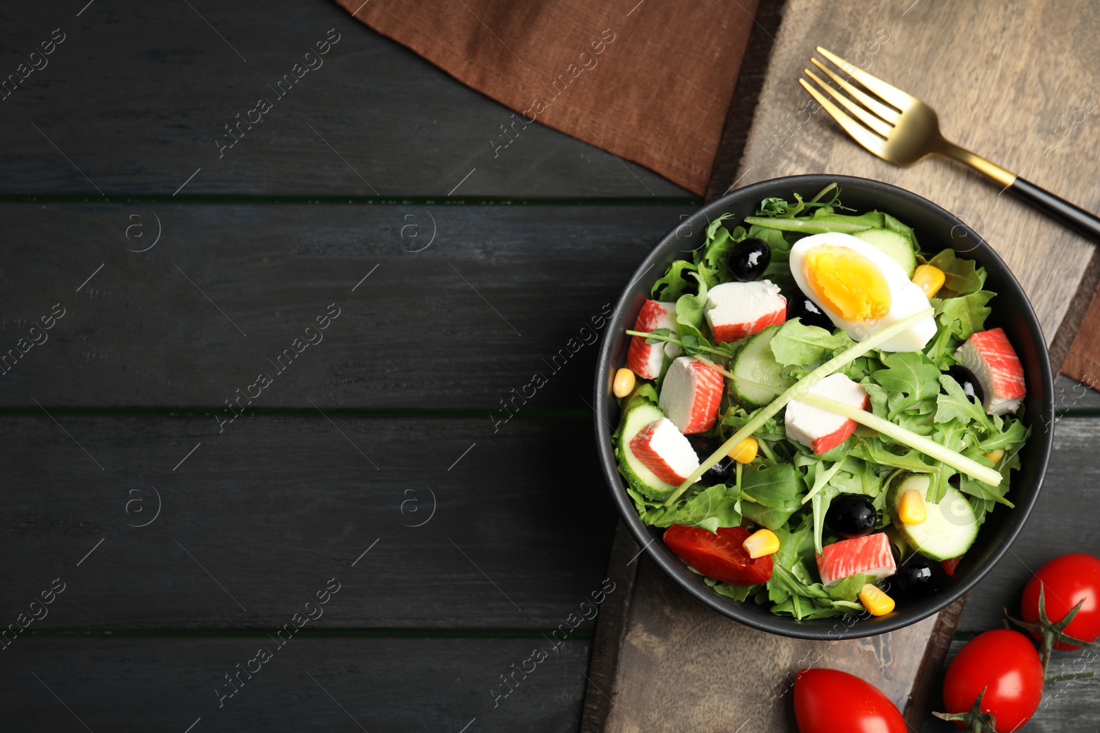 Photo of Tasty crab stick salad served on grey wooden table, flat lay. Space for text