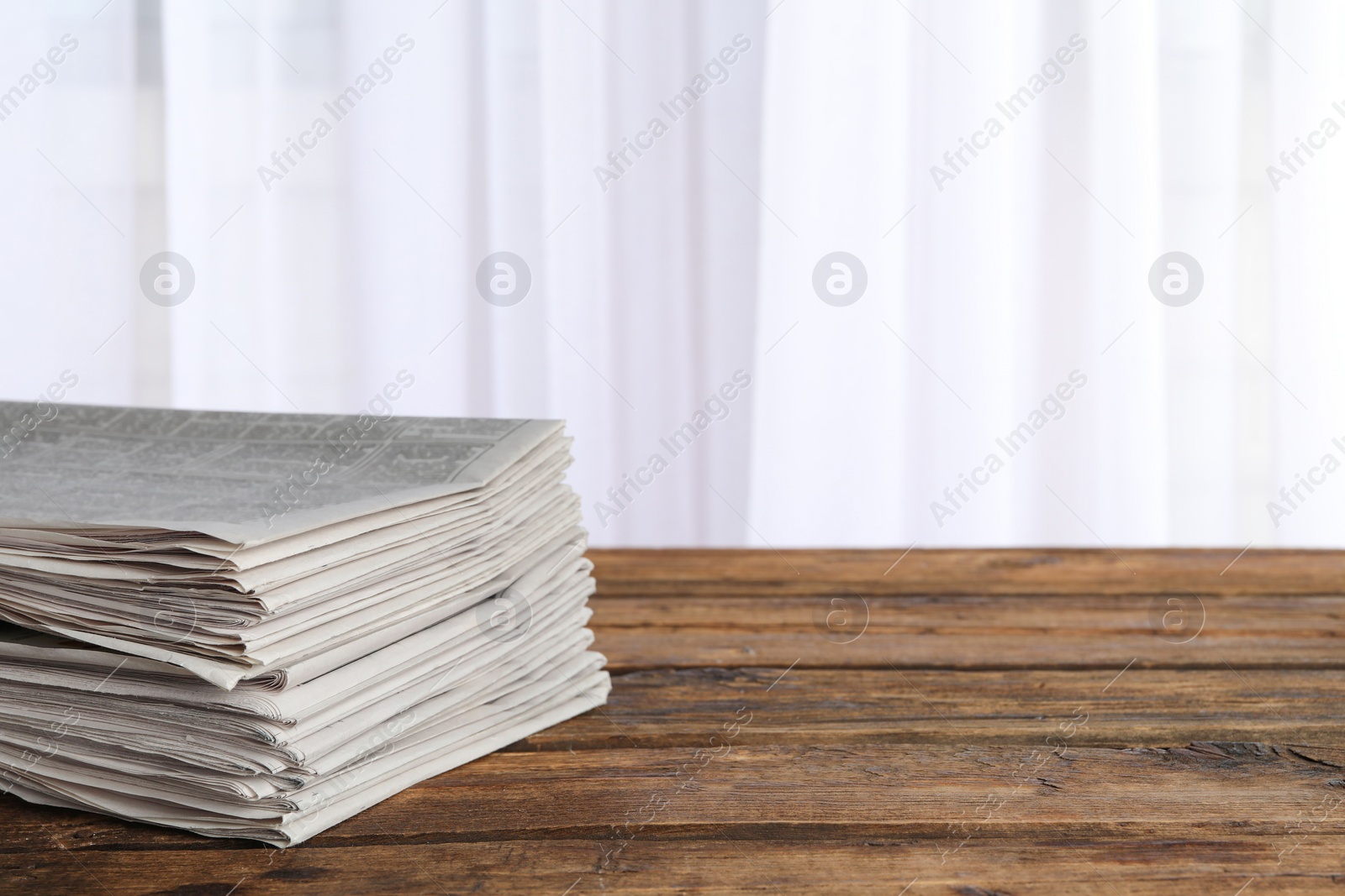 Photo of Stack of newspapers on wooden table, space for text. Journalist's work