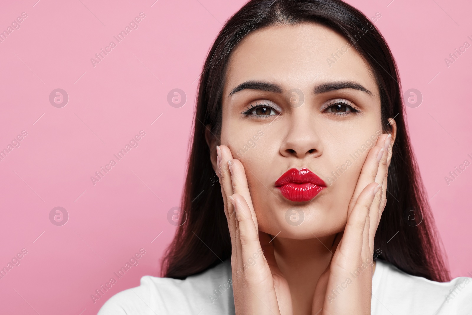 Photo of Beautiful young woman giving kiss on pink background, closeup