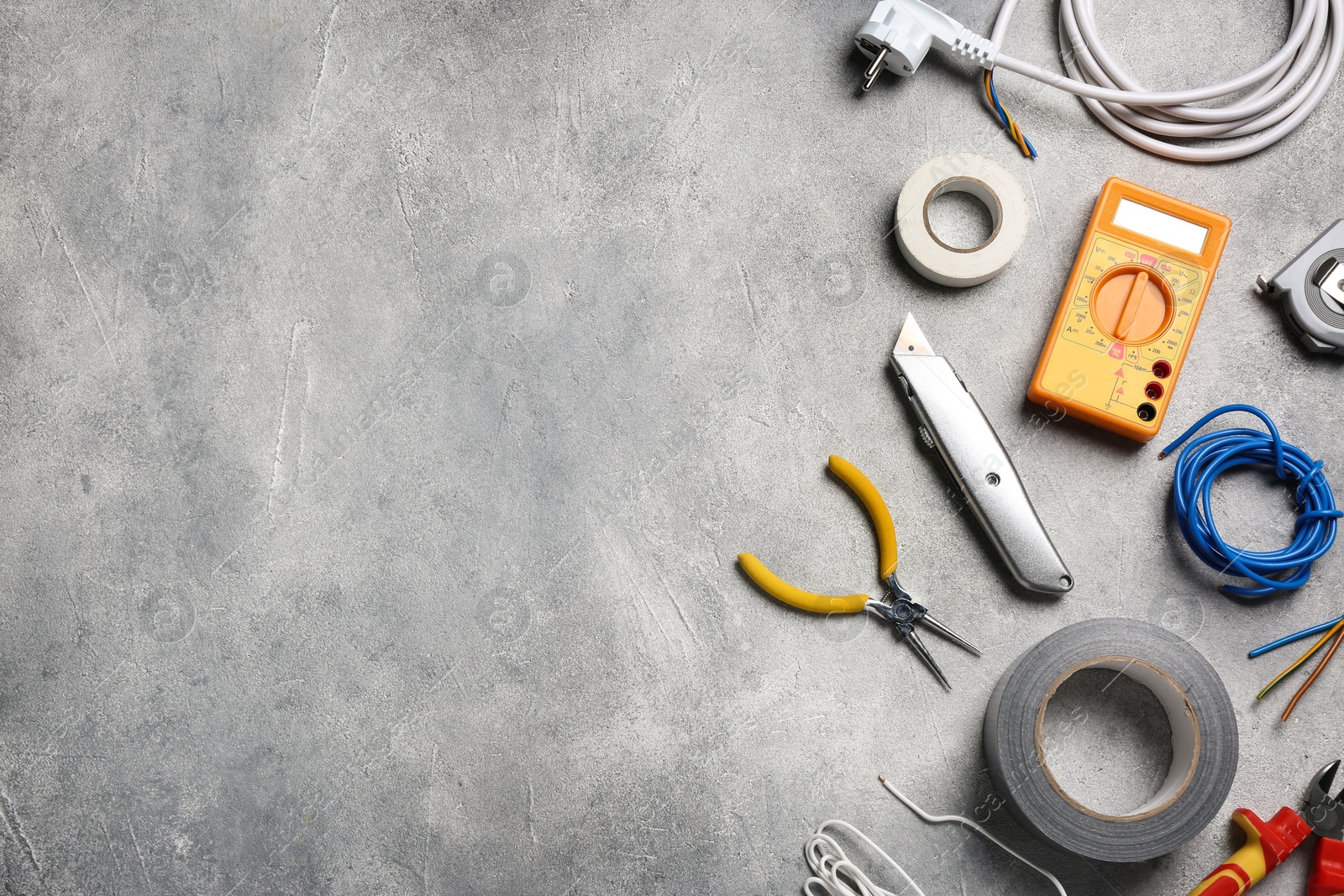 Photo of Wires and electrician's tools on grey table, flat lay. Space for text