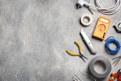 Wires and electrician's tools on grey table, flat lay. Space for text