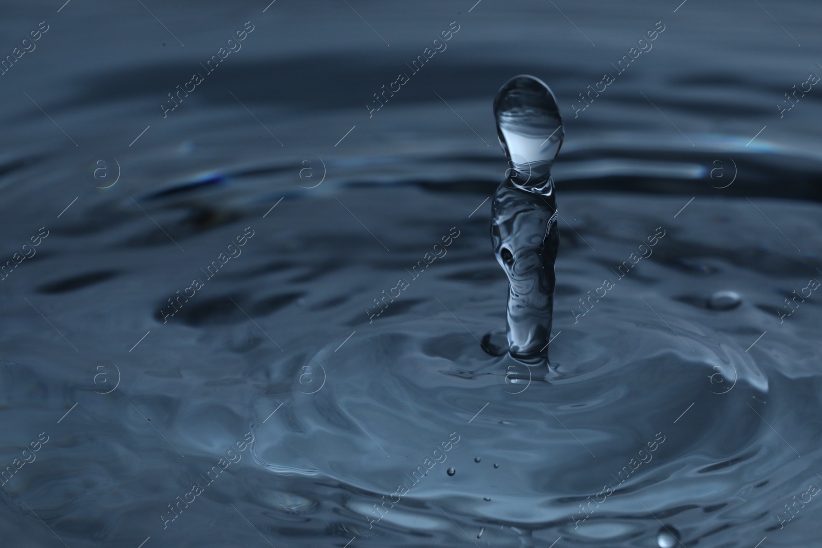 Photo of Splash of clear water with drops on dark blue background, closeup