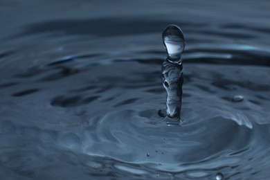 Photo of Splash of clear water with drops on dark blue background, closeup