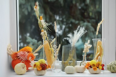 Photo of Composition with small pumpkins and beautiful flowers on white window sill indoors