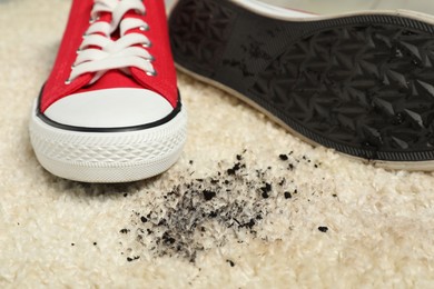 Photo of Red sneakers and mud on beige carpet, closeup