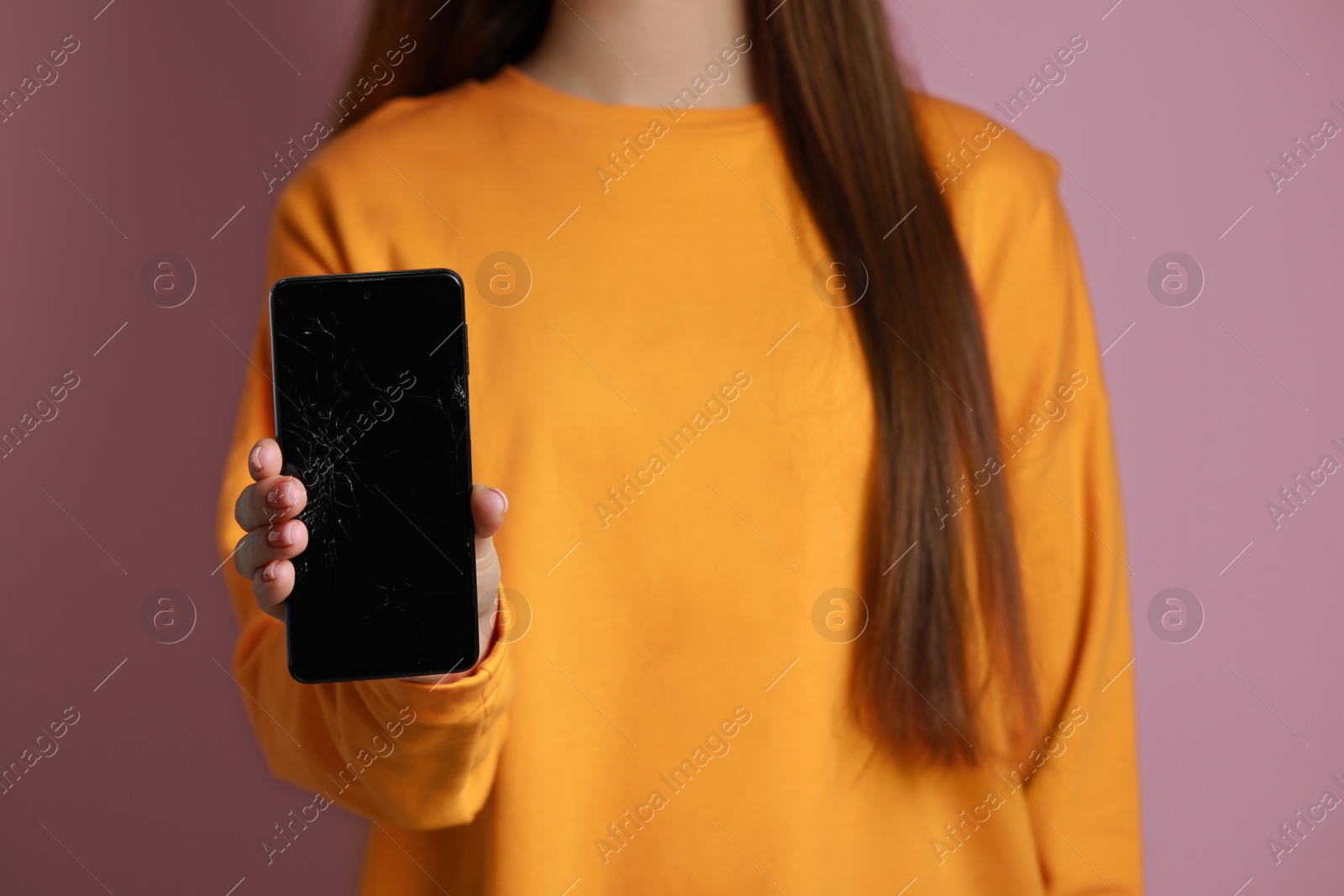 Photo of Woman showing damaged smartphone on pink background, closeup. Device repairing