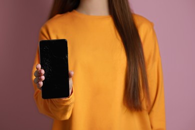 Woman showing damaged smartphone on pink background, closeup. Device repairing