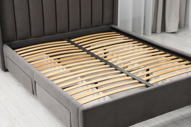 Photo of Modern bed with storage space for bedding under slatted base in room, closeup