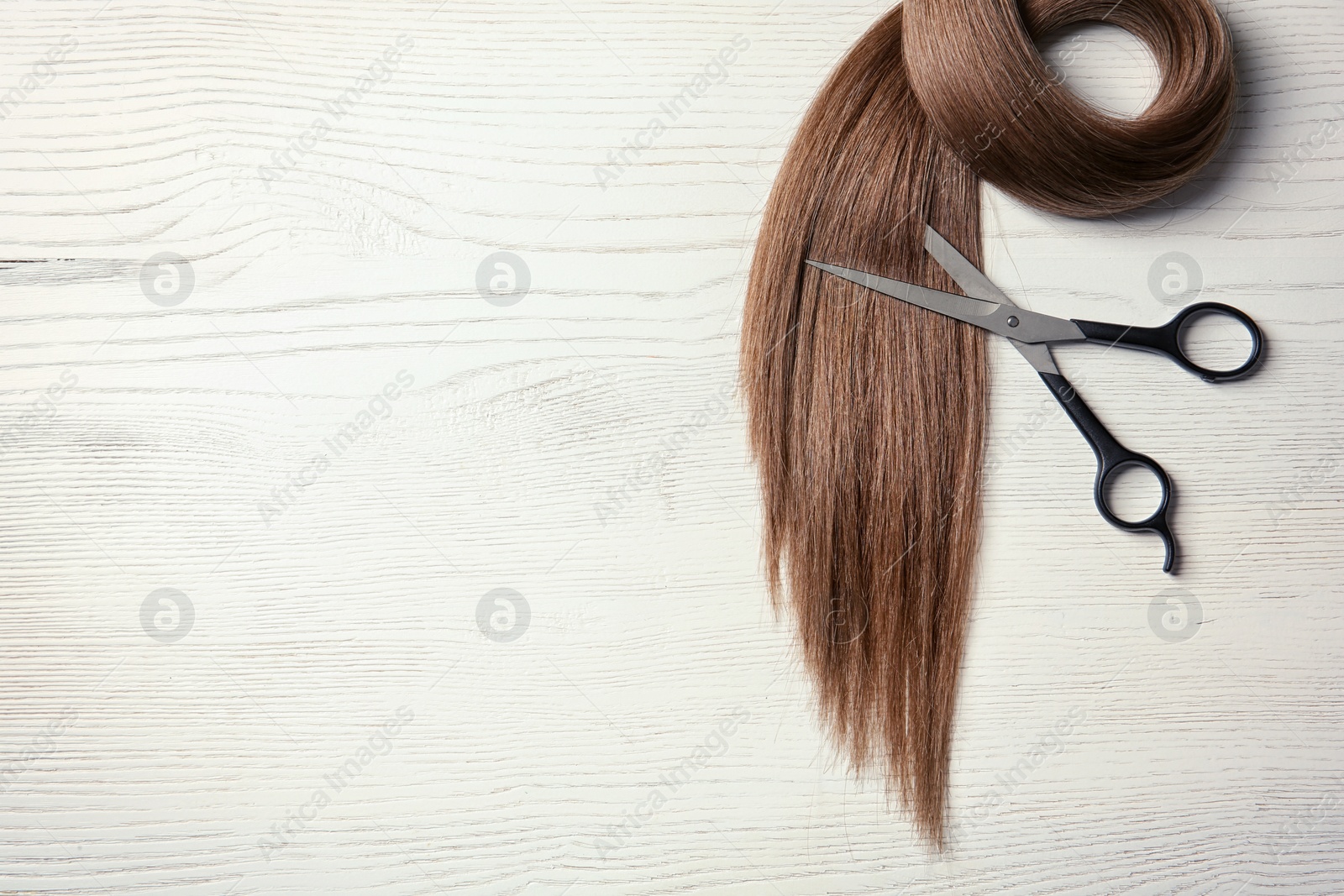 Photo of Composition with lock of brown hair on wooden background, top view. Space for text