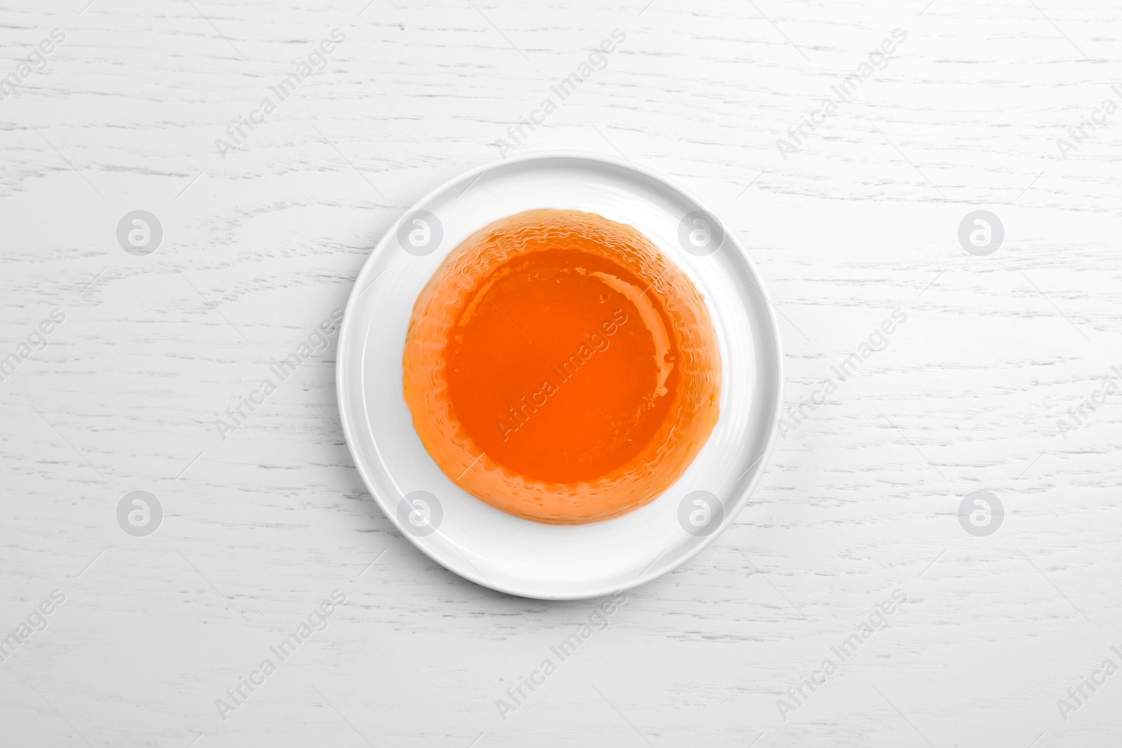 Photo of Plate with tasty fruit jelly on white wooden table, top view