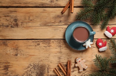 Photo of Delicious hot chocolate, fir branches, gingerbread cookies and cinnamon on wooden table, flat lay. Space for text