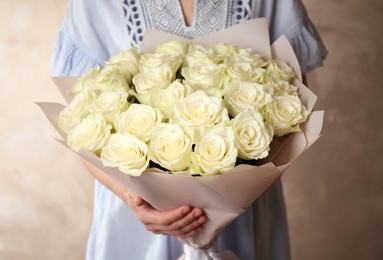 Woman holding luxury bouquet of fresh roses on light background, closeup