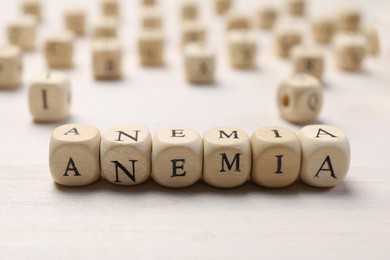 Photo of Word Anemia made with cubes on white wooden table