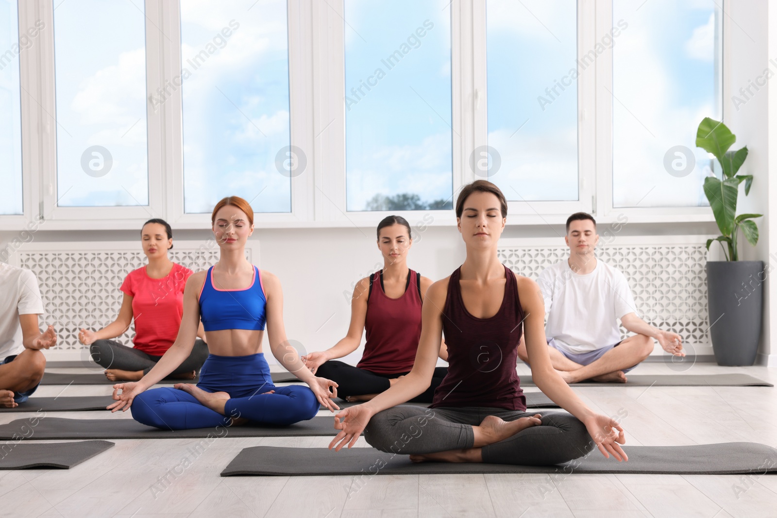 Photo of Group of people practicing yoga on mats indoors