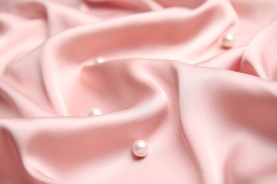 Photo of Many beautiful pearls on delicate pink silk, closeup