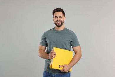 Happy man with folder on light gray background