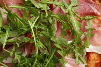 Tasty pizza with meat and arugula as background, top view