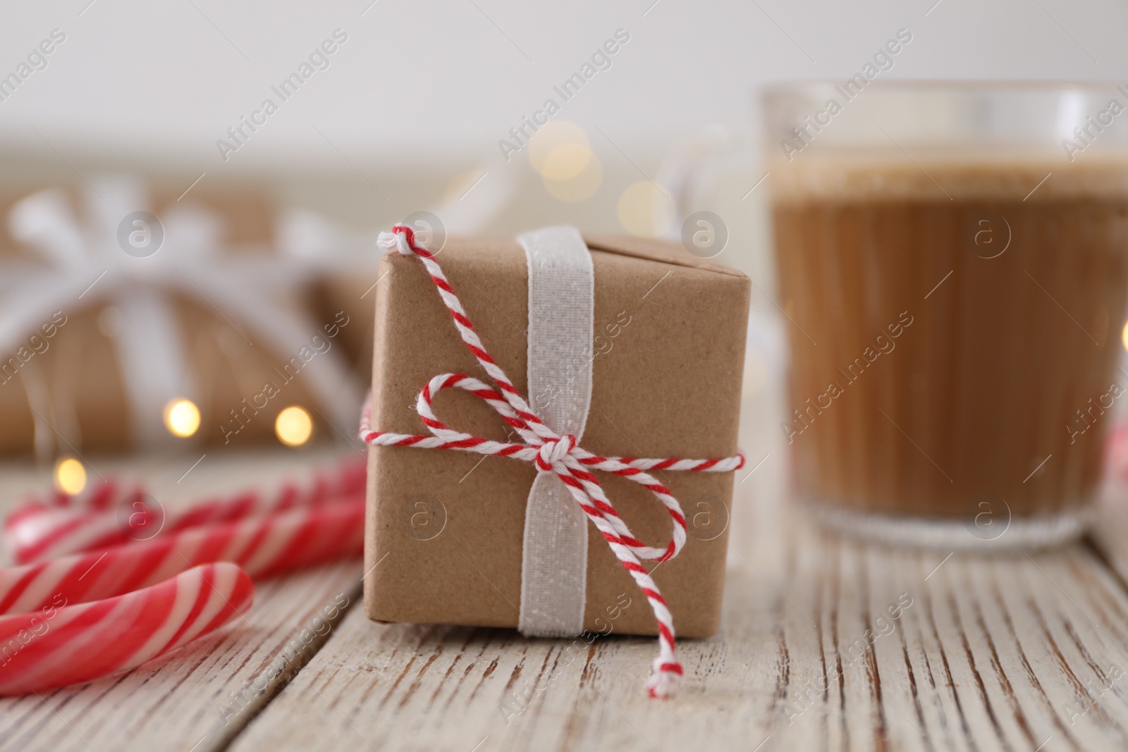 Photo of Christmas gift box and candy canes on white wooden table, closeup