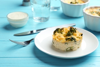 Photo of Tasty broccoli casserole served on blue wooden table