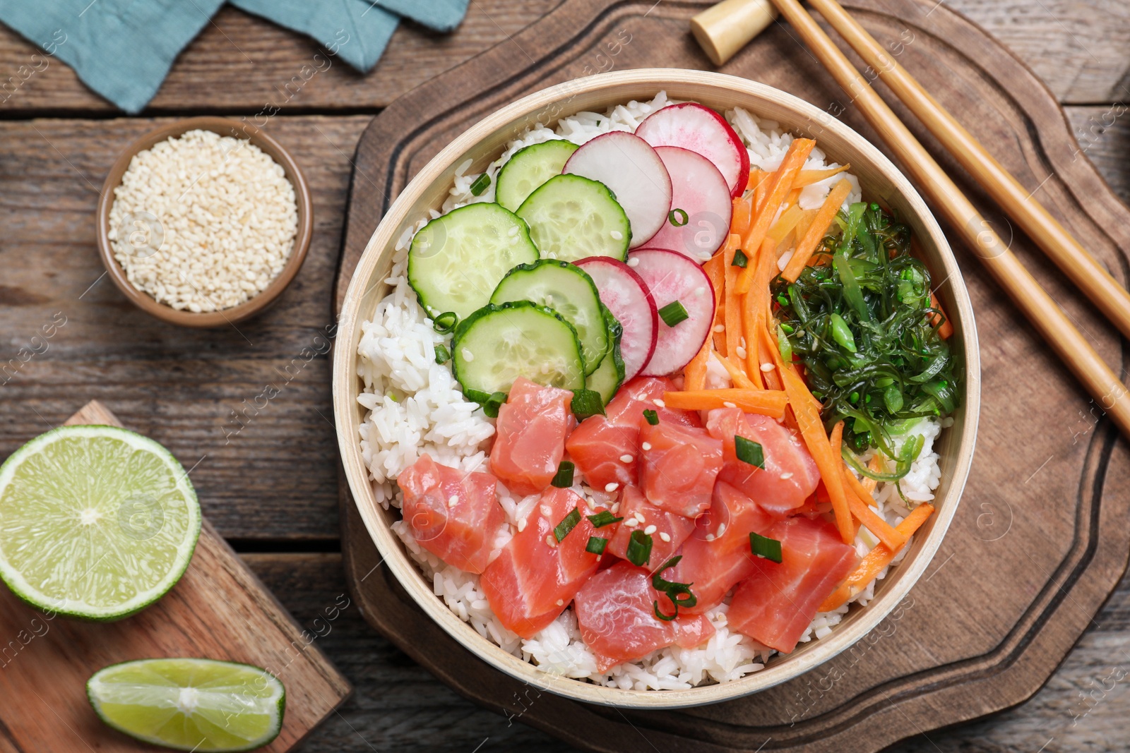 Photo of Delicious poke bowl with salmon and vegetables served on wooden table, flat lay