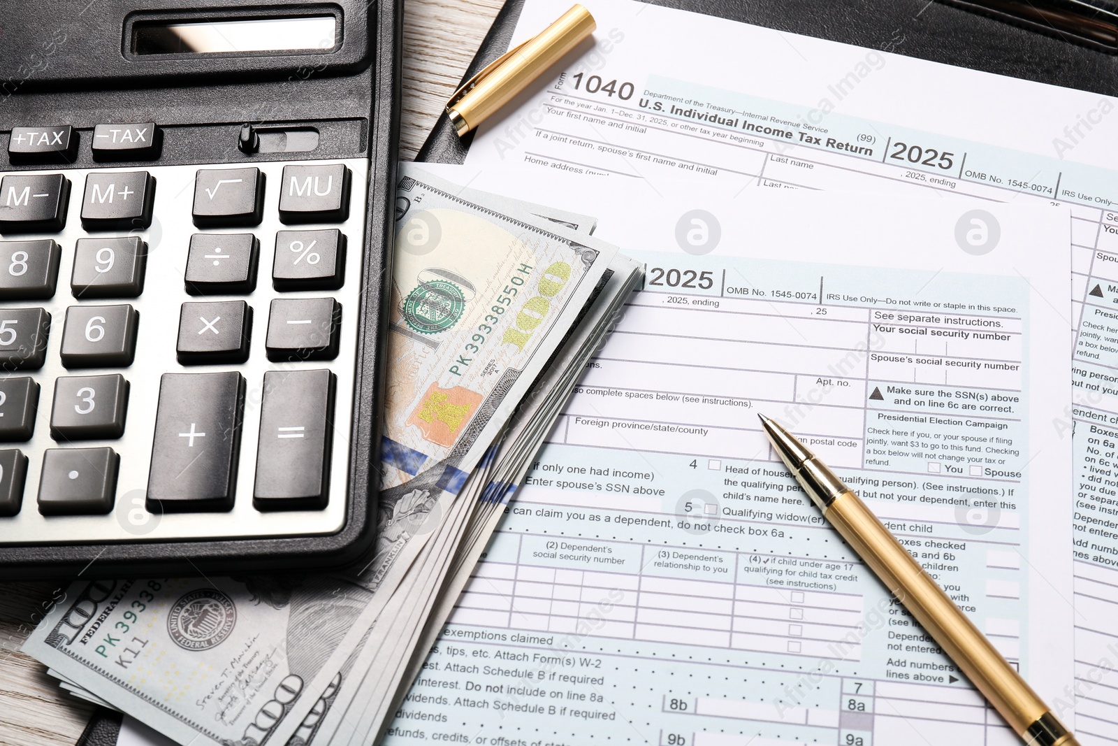 Photo of Tax return forms, dollar banknotes, calculator and pen on table, above view