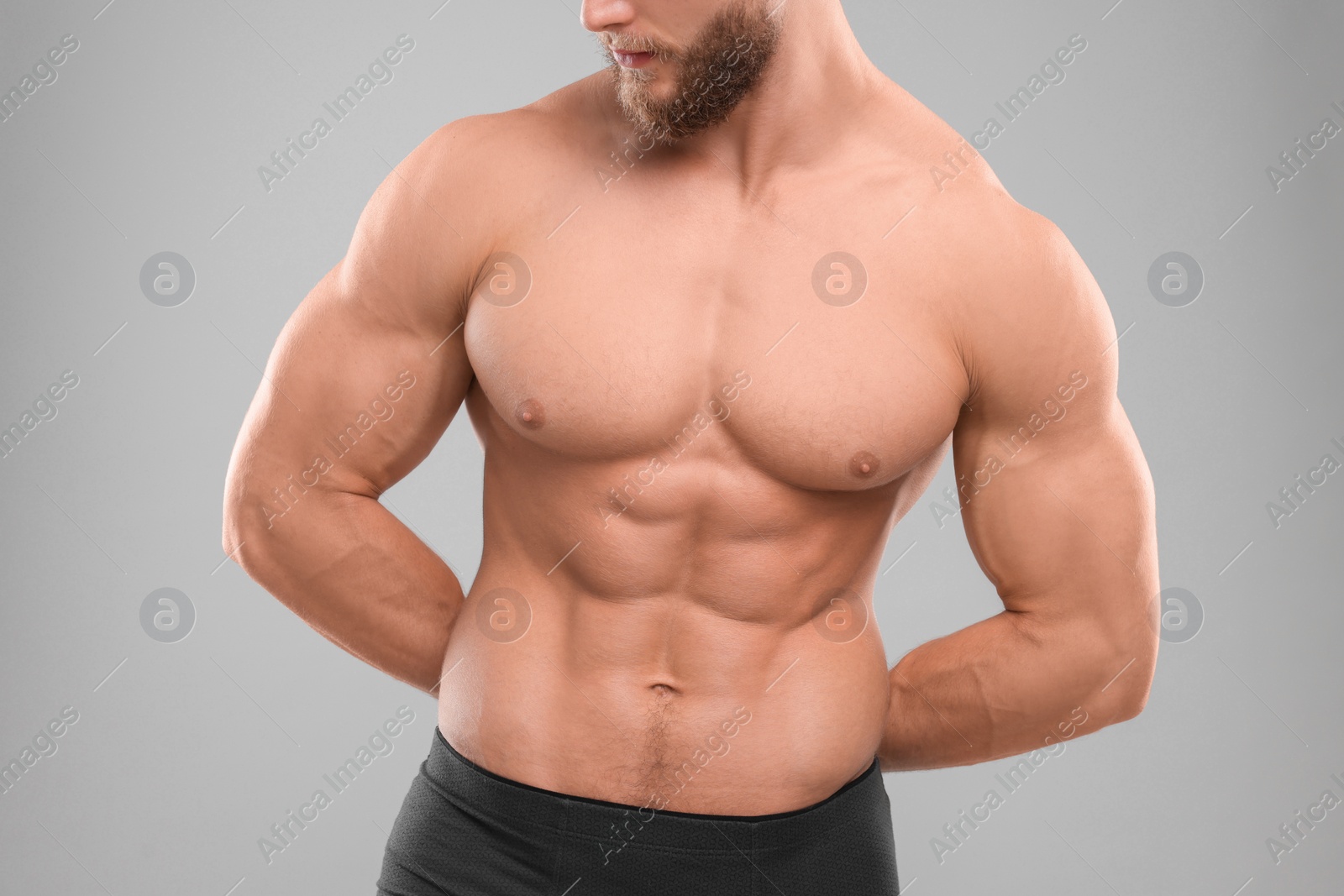Photo of Muscular man showing abs on light grey background, closeup. Sexy body