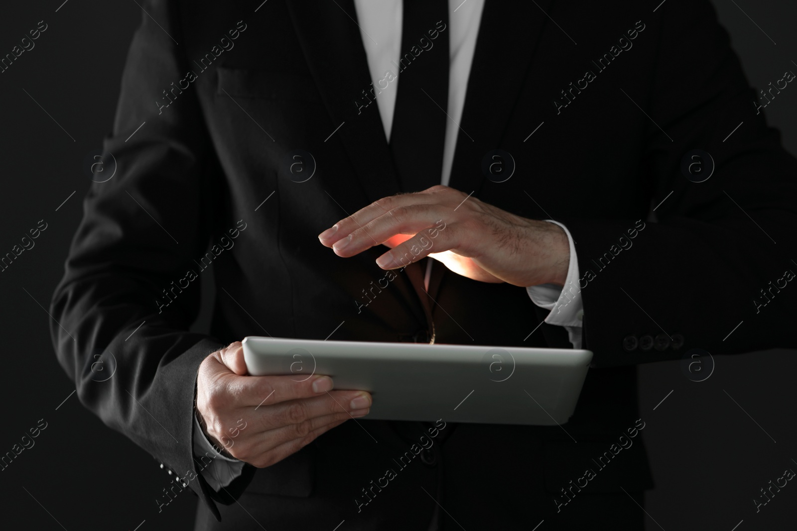 Photo of Closeup view of businessman using new tablet on black background