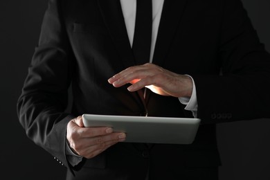 Photo of Closeup view of businessman using new tablet on black background