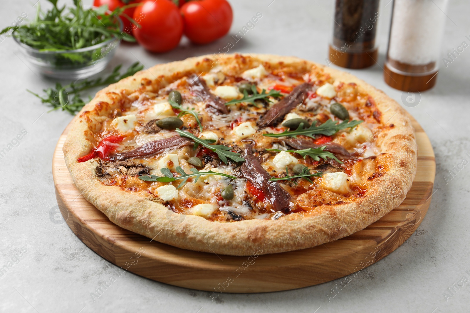 Photo of Tasty pizza with anchovies and ingredients on grey table