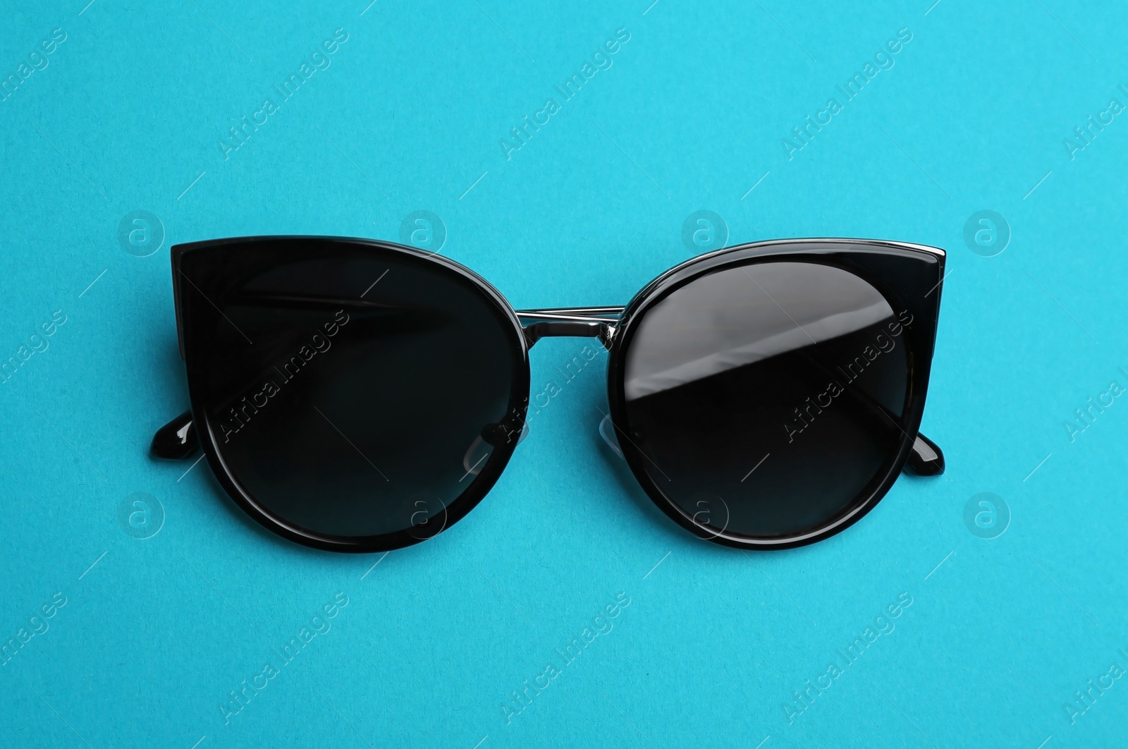 Photo of Stylish sunglasses on blue background. Fashionable accessory