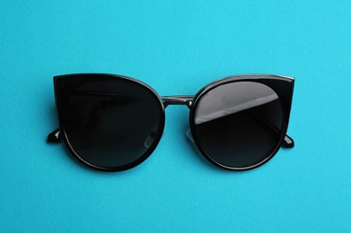 Stylish sunglasses on blue background. Fashionable accessory